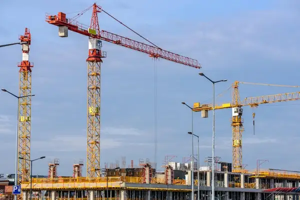 Construction site with cranes and building under construction, emphasizing the need for security guard services in urban development