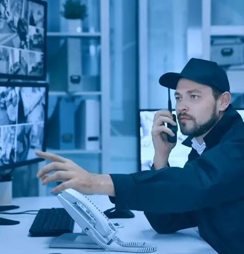 New York City Guard - Security guard at desk on phone, monitoring surveillance screens, emphasizing commitment to safety and security