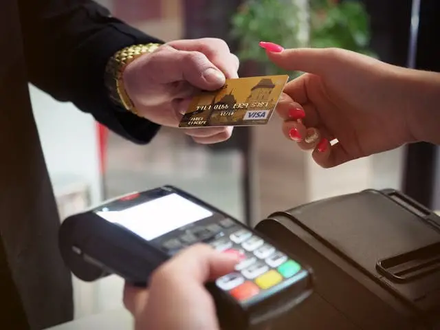 Close-up of hands using a credit card at a payment machine, highlighting the need for bank security guard services