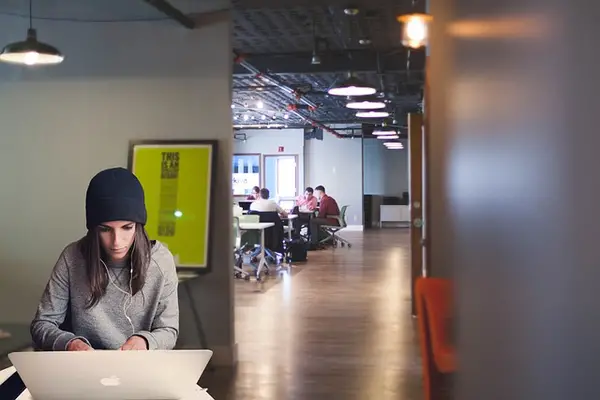 Individual working on laptop in modern office setting, highlighting the importance of security guard services for high-tech environments