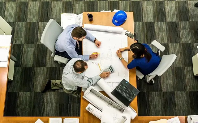 Three individuals at table with documents and blueprints, emphasizing the need for local government offices security guard