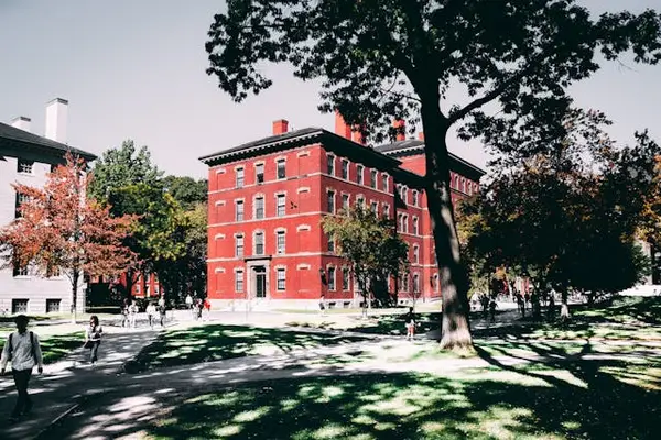 Red brick college building with white trim and trees in fall, highlighting the need for security guard services on university campuses