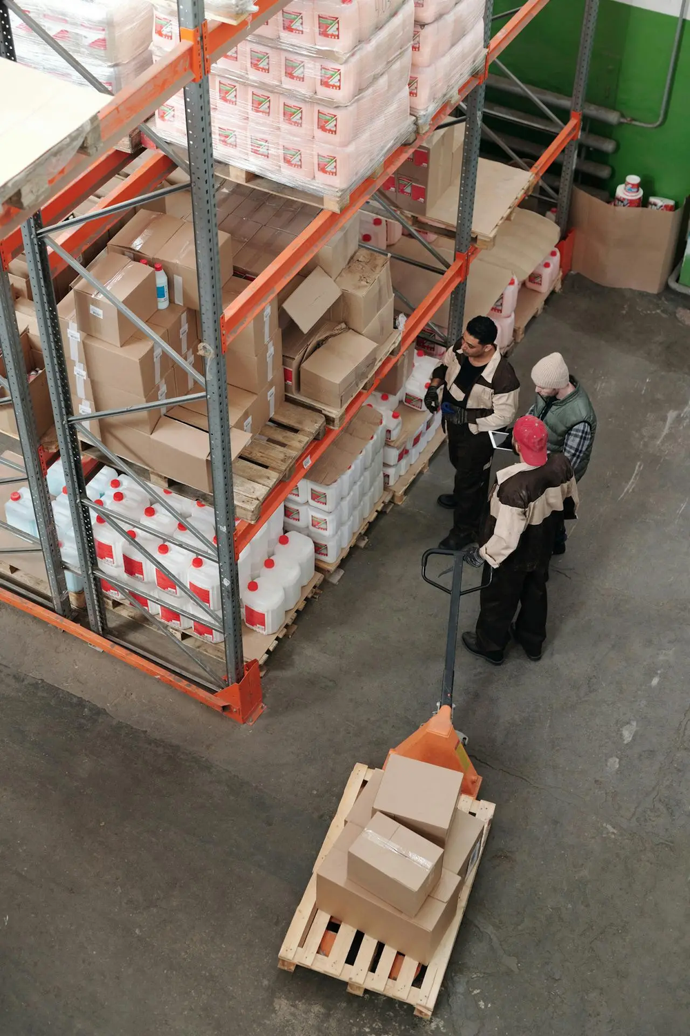 Two individuals in winter clothing using a pallet jack in warehouse, emphasizing the need for warehouse security guard