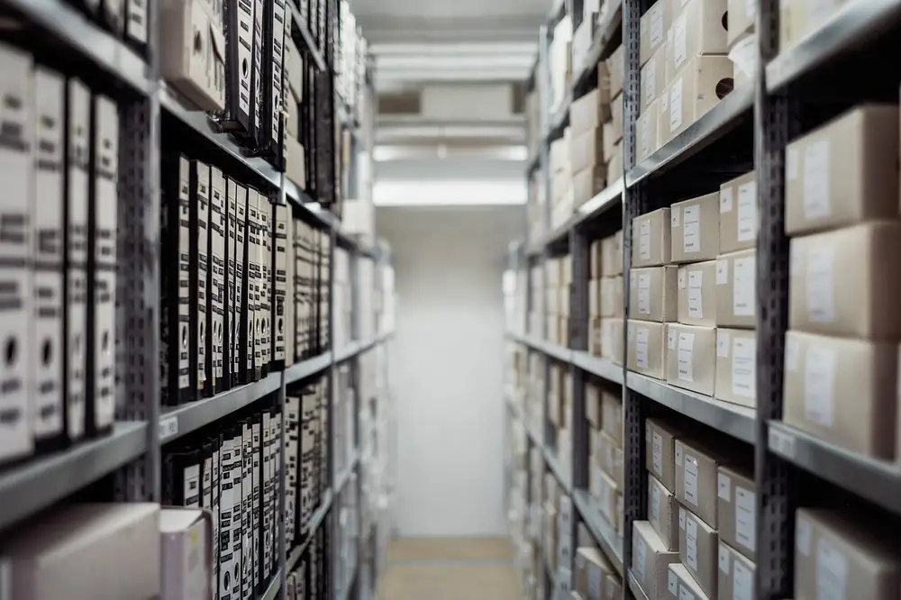 Organized storage area with tall shelving units filled with boxes, emphasizing the need for logistics security guard services