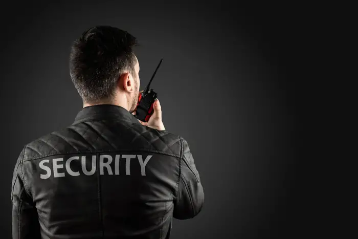 New York City Guard - Security professional in black jacket with 'SECURITY' holding walkie-talkie, top security guard companies NYC