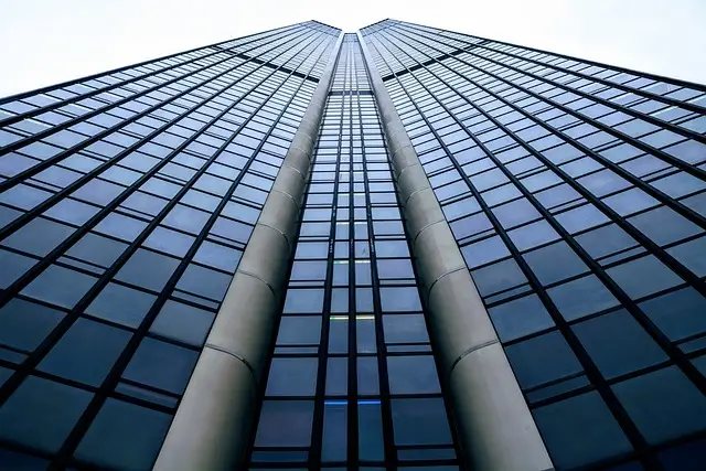 Low-angle view of tall skyscraper with glass facade, highlighting the need for commercial security guards in urban properties