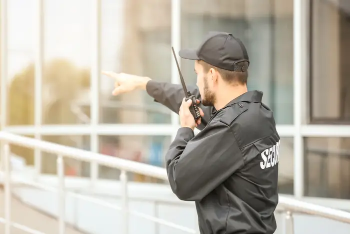 New York City Guard - Security guard in black jacket with 'SECURITY' holding walkie-talkie, monitoring outdoor environment