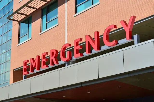 Exterior of hospital building with large 'EMERGENCY' sign, emphasizing the need for hospital security guard services