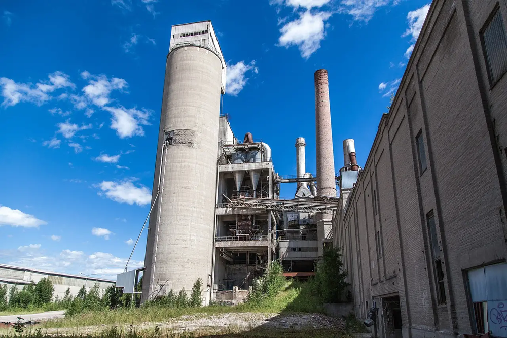 Abandoned industrial facility with tall tower and chimneys, emphasizing the need for manufacturing security services