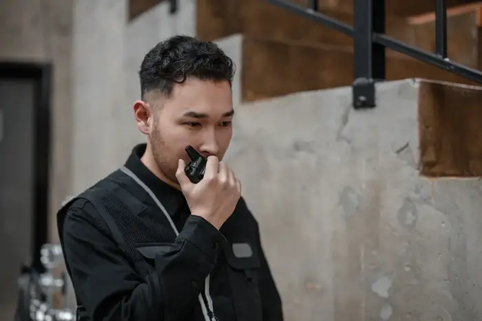 Unarmed security guard in black jacket with walkie-talkie in industrial setting, representing unarmed security guard services