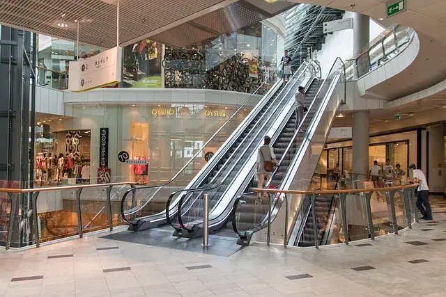 Indoor shopping mall with escalators and shoppers, highlighting the need for retail security services